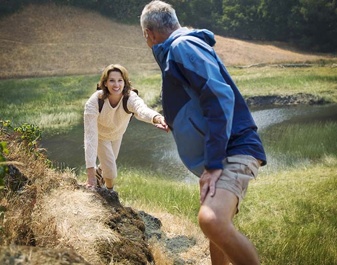Person helping another person climb a hillside outdoors